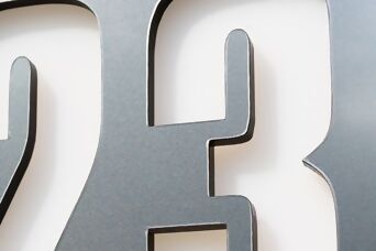 Nahaufnahme eines Metallschildes mit der Zahl 23, das klar und deutlich auf der Oberfläche sichtbar ist.