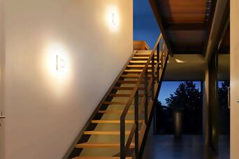 Moderne Wandleuchten entlang einer Treppe in einem stilvollen Innenraum, sorgen für angenehme und dezente Beleuchtung.
