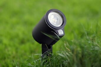  Moderner Steinel LED-Spot mit Sensor im Gras für gezielte Gartenbeleuchtung.