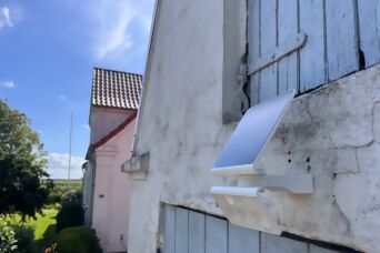 Solarstrahler von Steinel an einer rustikalen Hausfassade mit blauen Fensterläden – nachhaltige Beleuchtung im ländlichen Stil.