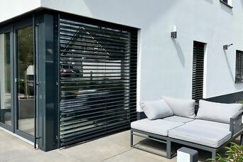 Moderne Terrasse mit stilvollen Steinel Außenleuchten an einer weißen Hausfassade.