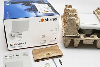Verpackungsinhalt eines Steinel XLED home 2 Strahlers mit plastikfreier, umweltfreundlicher Verpackung, bestehend aus Karton und Papiermaterialien.
